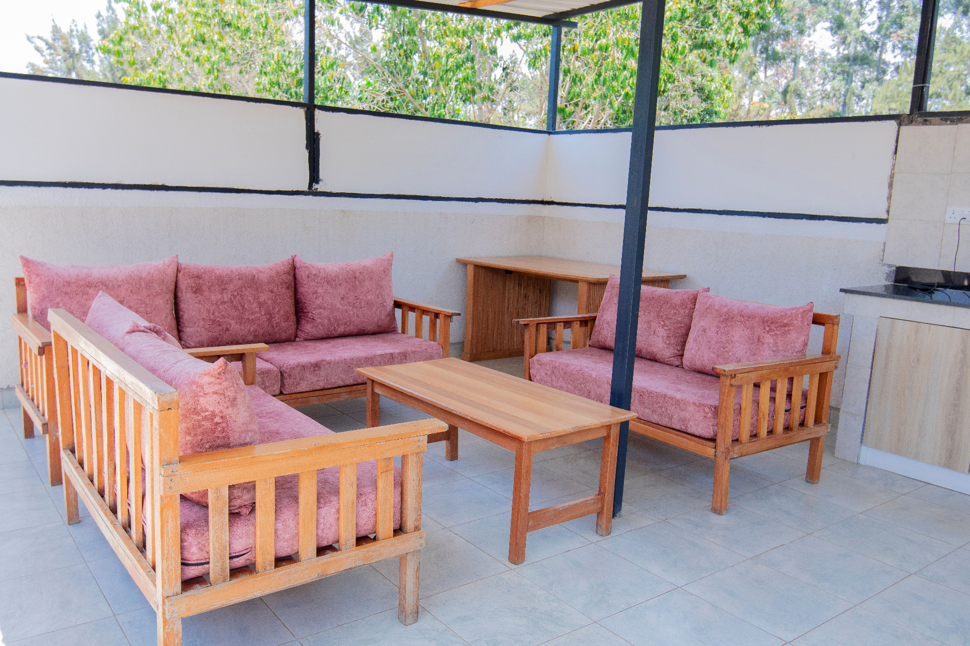 Rooftop lounge with wooden seating and pink cushions overlooking trees
