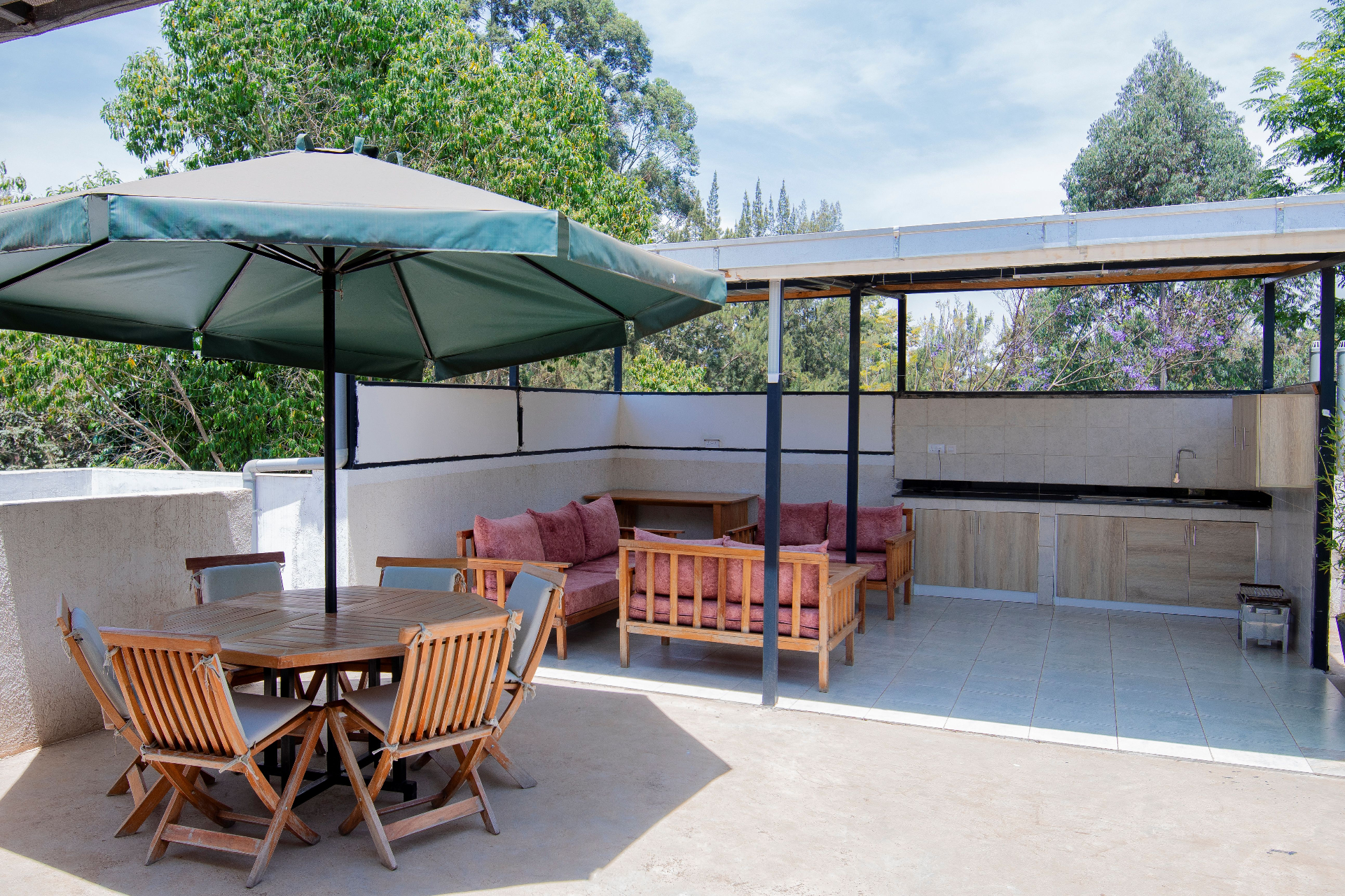 Spacious rooftop lounge with dining area, kitchen, and outdoor seating under canopy