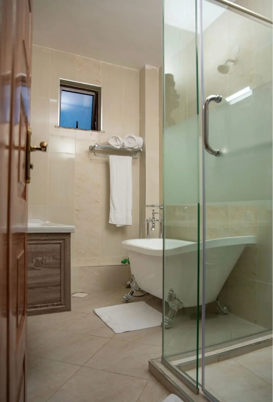 One-Bedroom Furnished – bathroom with clawfoot tub, glass shower, and plush towels